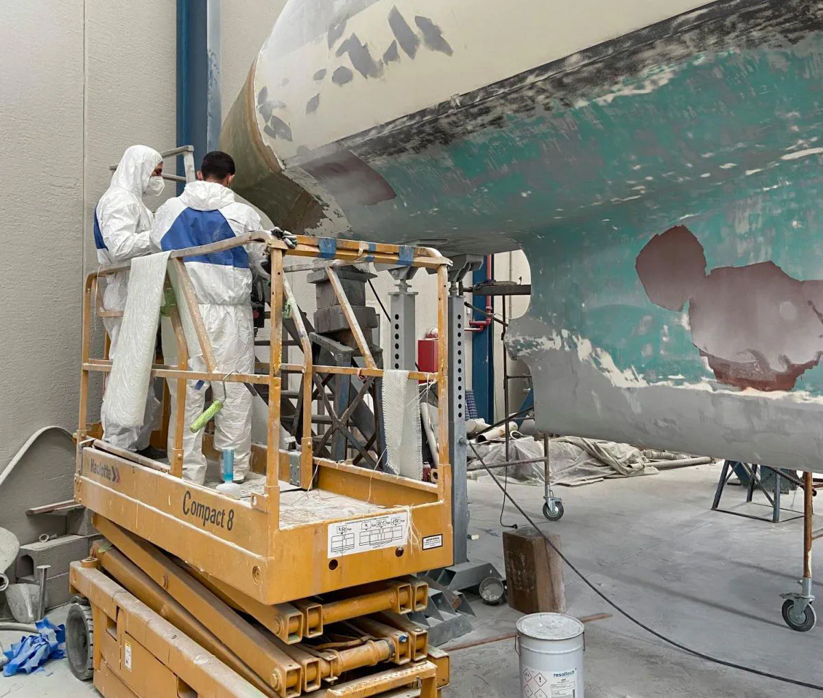 Shipyard workers repairing the hulls with fiberglass.