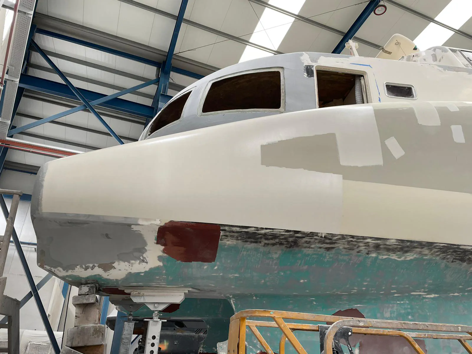 A close-up of the freshly repaired and primed fiberglass on the boat's hull.