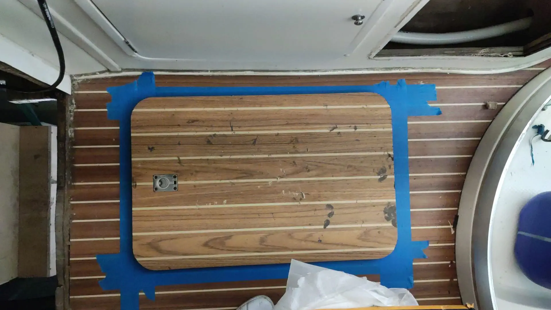 Marquage du plancher pour la découpe de la nouvelle trappe en utilisant une trappe existante comme gabarit.